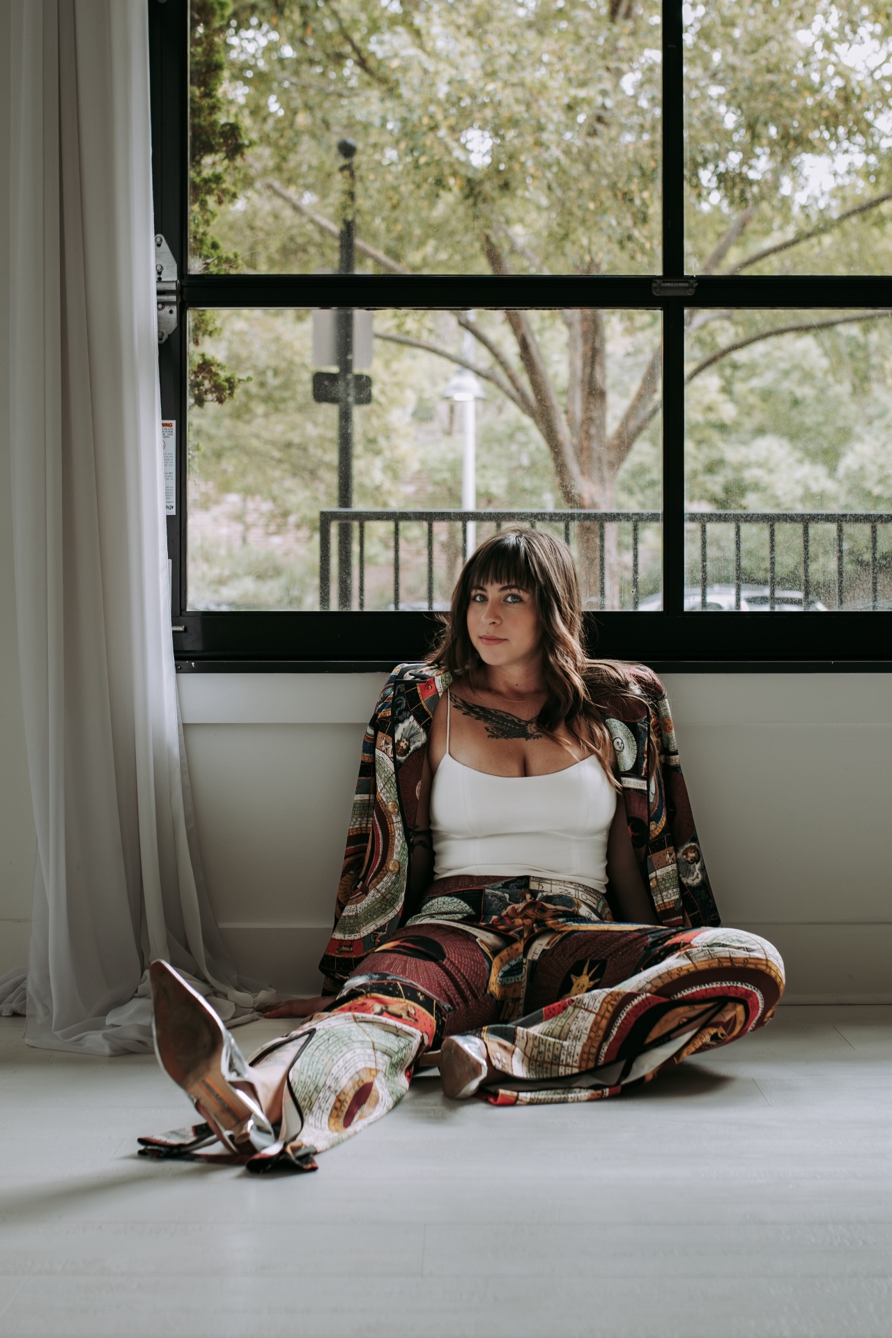 Gracie Stokes, founder of Wander the Stars, seated by a sunlit window in a celestial-print suit with silver boots.